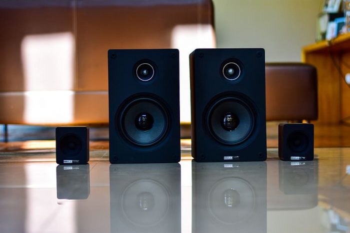 Black-colored dolby atmos speakers placed on the floor in a brightly-lit room. This is the top choice product for your home sound system