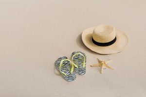 flip flops and hat in the sand