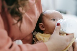 A mom feeding her child a bottle of the Loulouka formula, one of the best formula choices. 