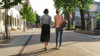 Two people walking down the street in the summer