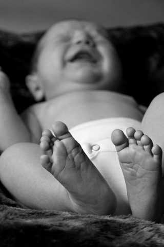 Photo of a baby crying while laying on the bed, due to a gassy tummy. 