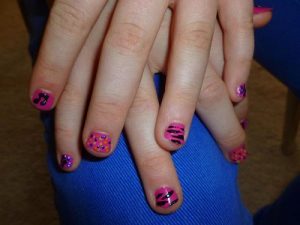 A woman with short nail types shows her best summer vacations nail designs. Her nail designs is a combination of many colors. 