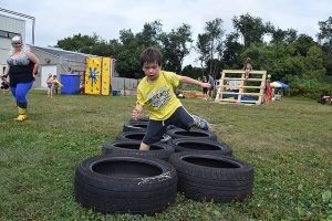 A child running through an obstacle course outside their backyard on a cloudy day.