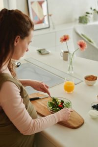 Woman preparing a green salad, rich in folic acid. This essential prenatal multivitamin is a crucial gestational supplement for the development of your precious baby.