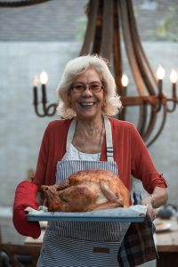 An image of a woman proudly presenting a golden-brown turkey fresh from the fryer