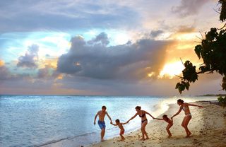 There are family holding hands together. They look happy while enjoying the company of each other. They are at the beach. 