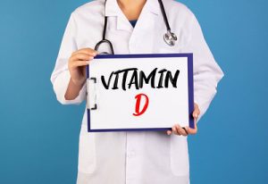 A doctor holding a clipboard that says Vitamin D. Supplementing this nutrient helps avoid deficiency. 