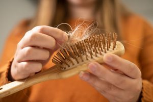 A woman pulling hair that accumulated in her hair brush.