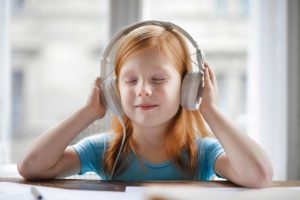 A young girl is listening to a song thru the headphone.