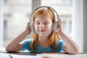 A young girl is listening to a song thru the headphone. 