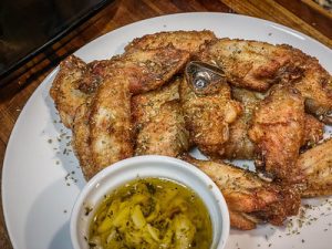 Crispy and tasty chicken wings prepared from air fryer Instant Vortex is plated with dipping sauce in a white plate and placed on the kitchen table. The Instant Vortex is one best air fryer to consider.