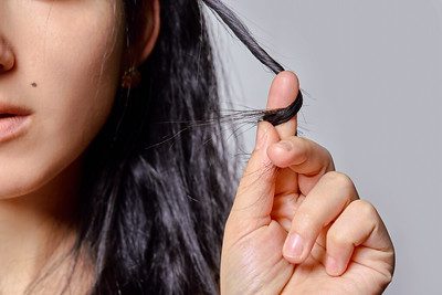 A person with long hair twirling a lock around her finger. Read this article to discover the best supplements for your hair.