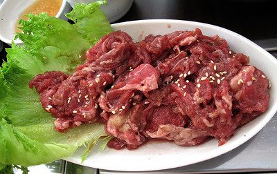 Air-fried bulgogi plated beautifully with lettuce in a while plate.