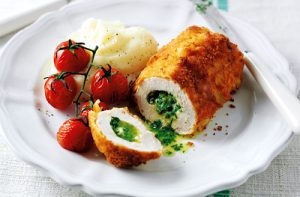 Air Fryer: A plate featuring a crispy air fryer chicken Kiev cut to reveal a herb butter center, accompanied by mashed potatoes and roasted cherry tomatoes on the vine.