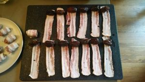 Plate of bacon strips and dates, ready to be wrapped. These perfectly wrapped dates in bacon strips are your ticket to a delectable culinary adventure.