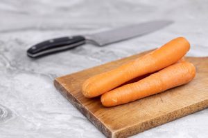 A carrot on top of the chopping board.