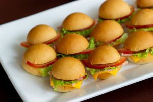 A platter of air fryer White Castle sliders cooked in an air fryer with lettuce, cheese, and tomato on a white rectangular plate, presented as appetizers or snacks. You can achieve this one with the help of a fryer or air fryer.