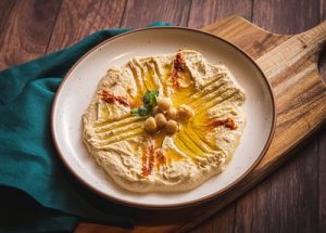 An image of a small bowl filled with creamy vegan ranch dip, surrounded by colorful vegetable sticks for dipping. The dip is smooth and creamy, with herbs and spices visible throughout, promising a flavorful and satisfying snack or appetizer