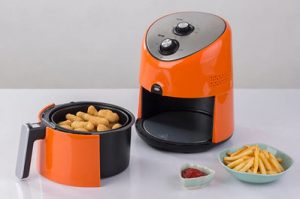 air fryer - An orange air fryer which was used to cook corn dogs and french fries.
