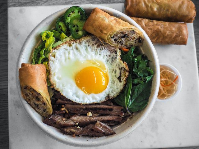 Delicious and healthy eggroll with egg, vegetables, and meat placed in a white bowl on the table. 