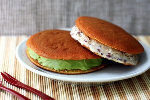 Air Fryer: A plate with two Japanese dorayaki pancakes filled with green tea ice cream and red bean paste, prepared in an air fryer.