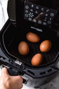Air Fryer. Four eggs in an egg fryer. The air fryer will be used to cook the eggs.