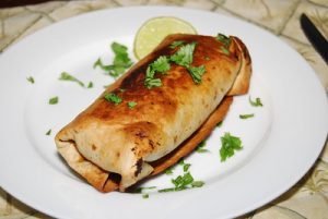 chimichangas in an air fryer plated using a white plate on top of a kitchen table