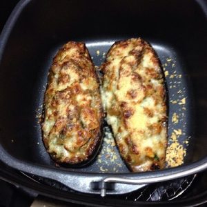 Air Fryer: Two halves of stuffed eggplants with melted cheese on top, cooked to a golden-brown finish in an air fryer basket.