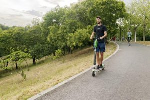 A man riding down an empty street surrounded by trees and greenery