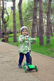 This is a little boy playing in the park, riding in his scooter. He surely loves playing in the park.