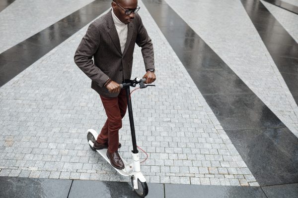 A brown man is testing a scooter for a senior.