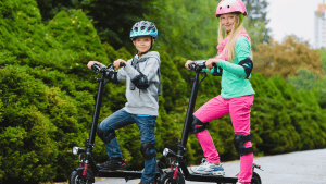 Two kids are on their scooters.