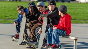 Gathering in camaraderie, a group of children sits and chats, clutching their skateboards, poised to demonstrate skating tricks fitness advantages 