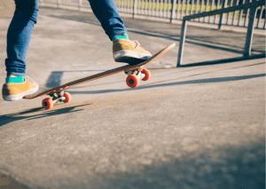 There are two fee riding an orange skateboard. This picture was taken in skateboard park. 