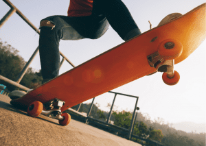 A half body of a person riding and doing skate tricks in an orange skateboard. Adults can also try skateboard riding. 