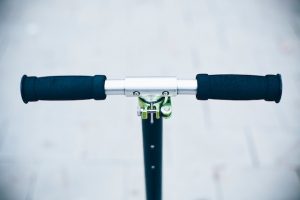 Black scooter handle resting on a textured road