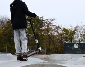 A man wearing a black jacket rides his scooter for camping. 