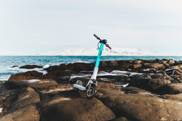 A scooter parked on a rocky area near a body of water