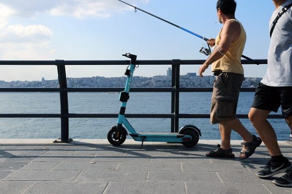 A blue escooter parked on a bridge overlooking a body of water