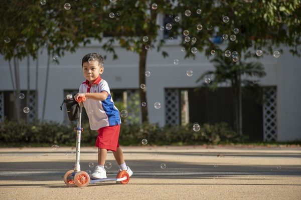 Child with a red scooter at the park