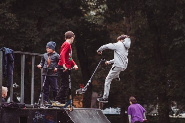 Children performing tricks with their scooters.