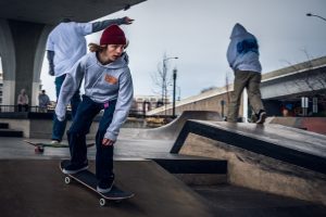 A group of skilled skateboarders practicing their tricks at a vibrant skatepark. With skateboards mid-air, they execute skateboard flips and spins, showcasing impressive skate control and skate balance. The concrete landscape for skateboard is adorned with skateboard ramps and skateboard rails, creating an energetic atmosphere as the skaters display their skateboard passion and mastery of skateboarding.