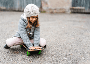 A girl enjoys skateboarding during cold weather. 