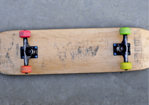 A skateboard with colorful wheels placed upside down on the floor. 