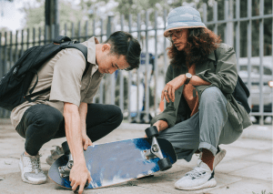 Two boys holding a skateboard.