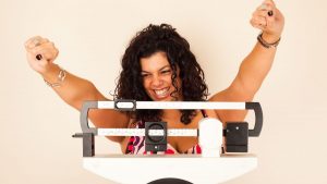 A beaming woman celebrates her successful weight loss journey through scooter riding.