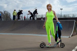 A woman with a scooter doing her fitness routine in the park.