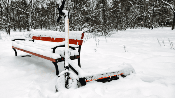 There is a scooter and bench with lots of snow. a