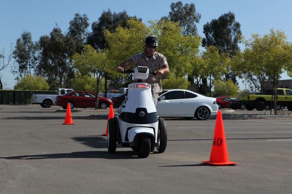 Muscled man riding a scooter. The scooter has three wheels making it the best for beginners. 