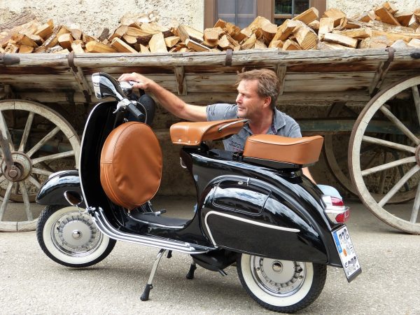 A man inspecting his scooter. It has unique design. 